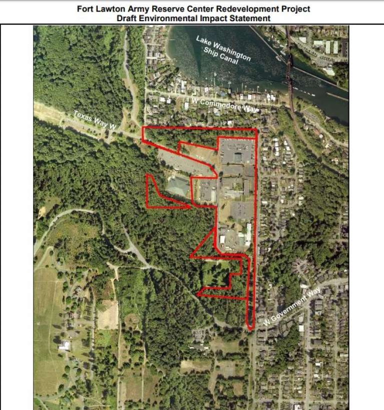 An aerial view of the mostly-paved Fort Lawton property demarcated by a red outline, showing its clear separation from the forested park area.