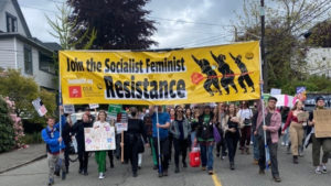 Seattle DSA members and community members marching with the banner, Join the Socialist Feminist Resistance